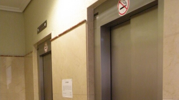Ein Flur mit zwei Aufzügen, wobei ein Aufzug ein Rauchverbot-Schild darüber hat.