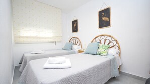 A hotel room with two beds, each with a wooden headboard and a quilted bedspread. There is a window with a patterned blind, and two wall-mounted wall art pieces depicting a bird. - Marina Baixa 3D in Cala de Finestrat (Finestrat)