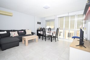 A modern living room with a sofa, a coffee table, and a dining area with chairs and a table. - Marina Baixa 3D in Cala de Finestrat (Finestrat)