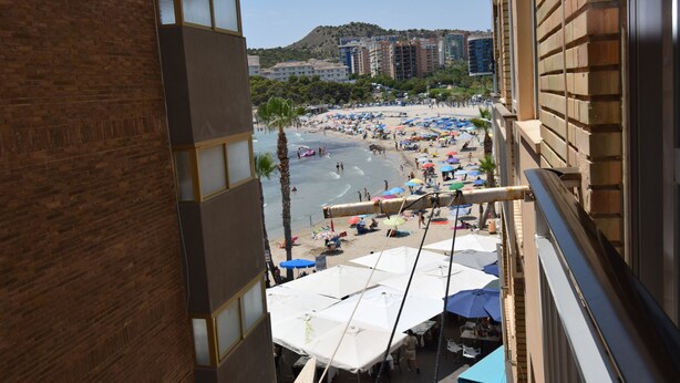 A view of a beach from a balcony with umbrellas and beachgoers. - Marina Baixa 3D in Cala de Finestrat (Finestrat)