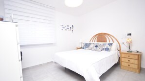 A bedroom with a bed, bedside table, lamp, and wall decorations. - Marina Baixa 3D in Cala de Finestrat (Finestrat)