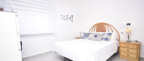 A bedroom with a bed, bedside table, lamp, and wall decorations.