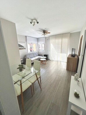 A modern living room with a glass dining table, a sofa, and a ceiling fan. - DON Paco 2B in Benidorm (Benidorm)