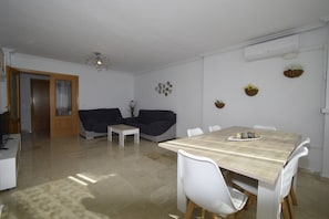 Un salon moderne comprenant un coin repas, un canapé, une table basse et un lustre.