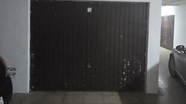 A parking garage with a closed black gate, tiled floor, and a car parked to the right. - Gemelos 5 4C in Benidorm (Benidorm)