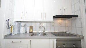 A modern kitchen with white cabinets, a stainless steel sink, a coffee maker, and a built-in oven. - Gemelos 5 4C in Benidorm (Benidorm)