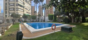 A swimming pool surrounded by greenery and tall buildings. - Gemelos 5 4C in Benidorm (Benidorm)