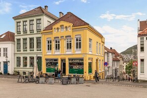 Un bâtiment jaune, orné d’enseignes indiquant la présence d’un café et d’un bistrot, et entouré d’autres bâtiments historiques.