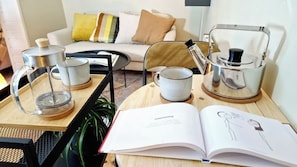 Un salon chaleureux avec un canapé, une table basse sur laquelle repose un livre et une bouilloire.