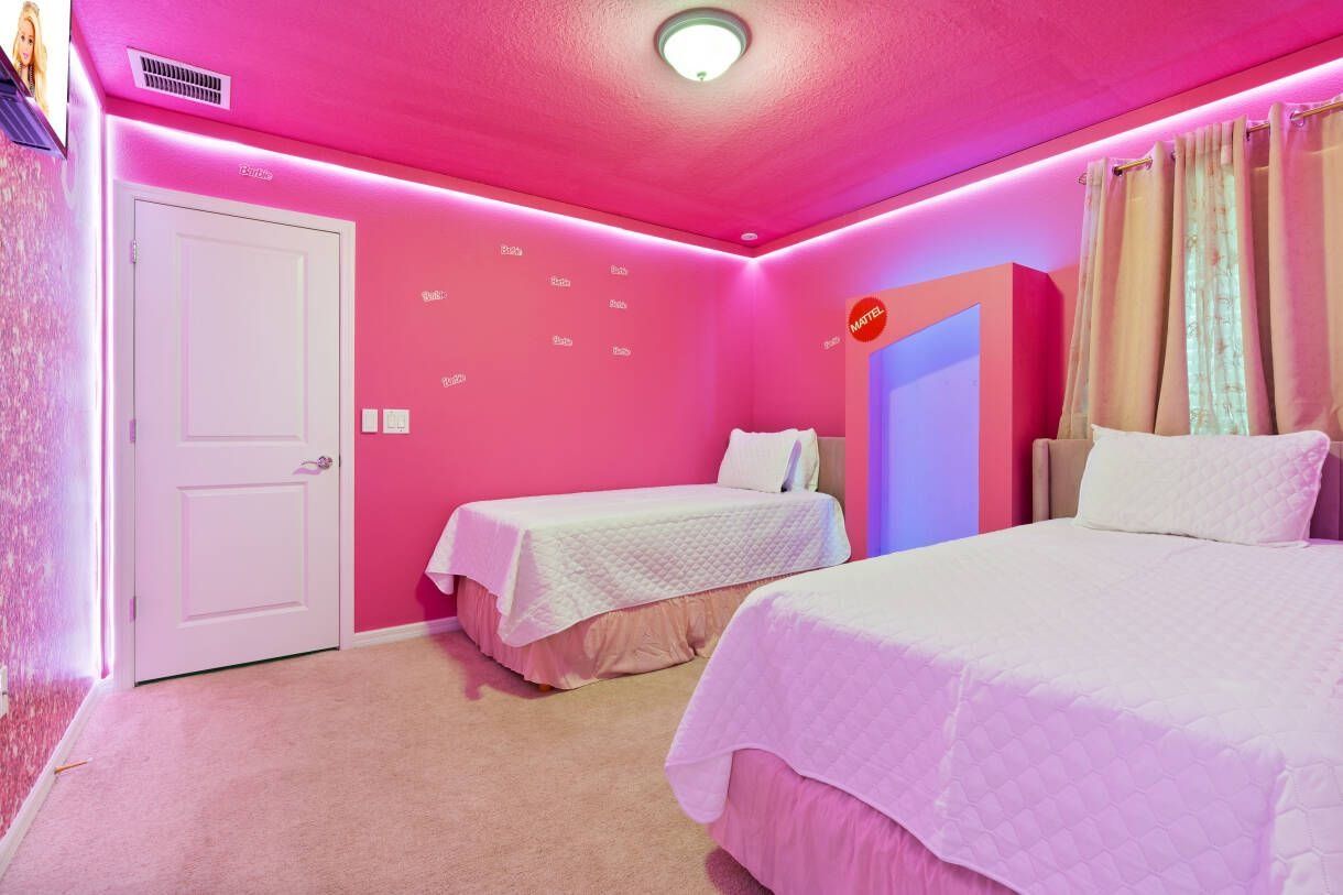 Una habitación con dos camas, una puerta blanca y una pared con un letrero rojo.
