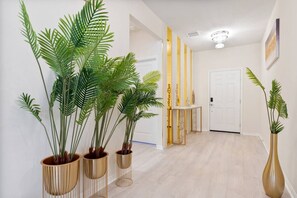 A hallway with potted plants, a white door, and a light-colored floor. - 10br Villa w/ Star Wars Theater & Game Room (Davenport)