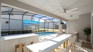 A modern pool area with a glass enclosure, a ceiling fan, and a view of a mountainous landscape. - 10br Villa w/ Star Wars Theater & Game Room (Davenport)