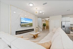 A modern living room with a large flat-screen TV, a fireplace, and a white sofa. - 10br Villa w/ Star Wars Theater & Game Room (Davenport)