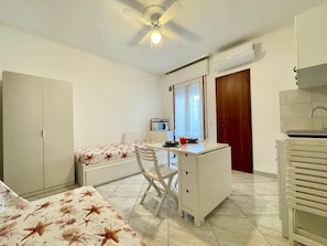 Ein gemütliches Zimmer mit Bett, Schreibtisch, Stuhl, Deckenventilator, Mikrowelle und Fenster.