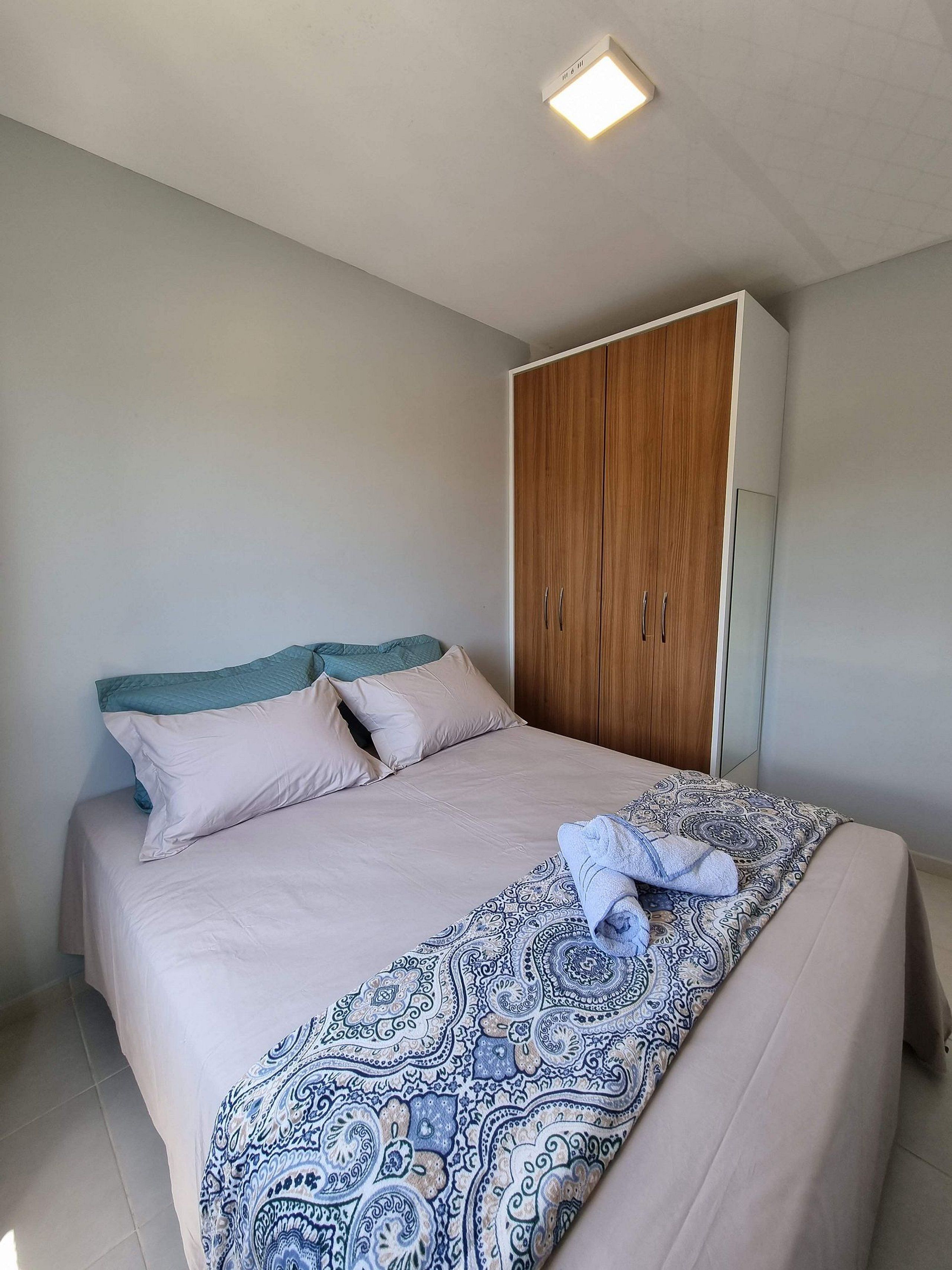 A bedroom with a bed, a wardrobe, and a ceiling light.