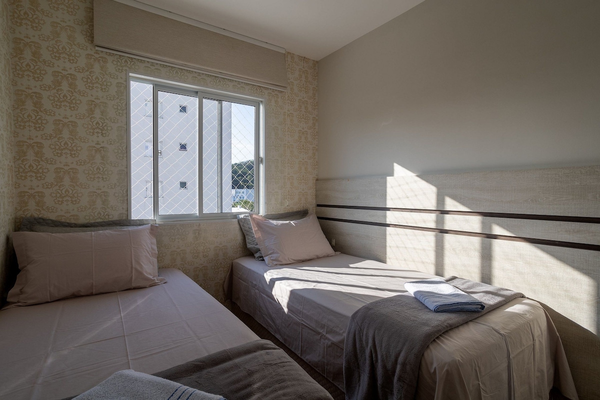 Una habitación con dos camas, una ventana y papel tapiz estampado.