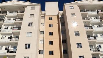 Un edificio residencial de varios pisos con balcones, una entrada principal y cielo despejado.