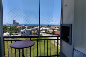 Ein Balkon mit Tisch, mit Blick auf eine Wohngegend mit Gebäuden und blauem Himmel.