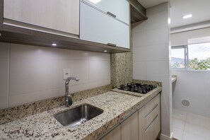 A kitchen with a granite countertop, stainless steel sink, and a gas stove. - Curta Praia do Quilombo - Palladium (Penha)