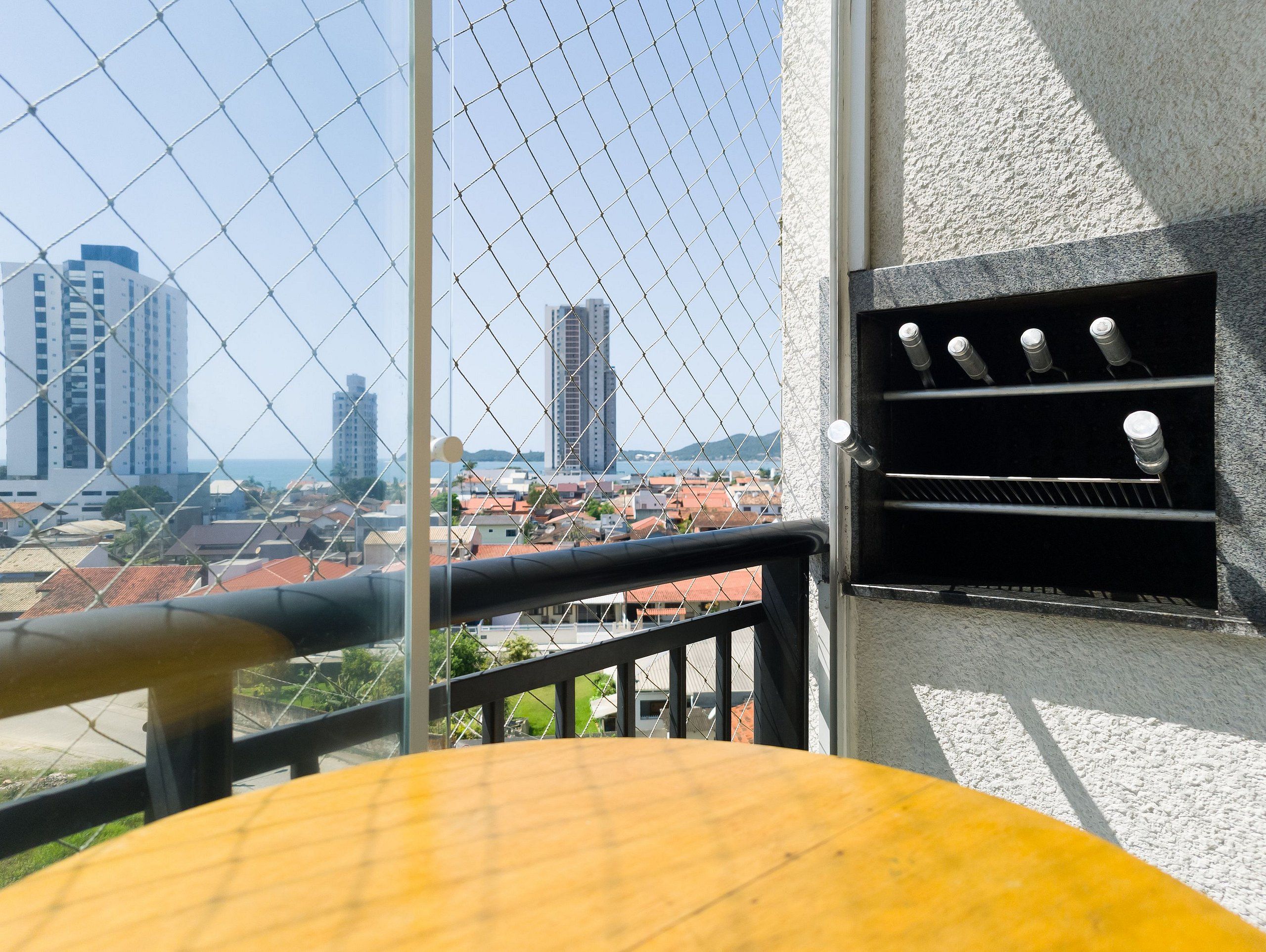 A balcony with a view of a cityscape, including tall buildings and a body of water.