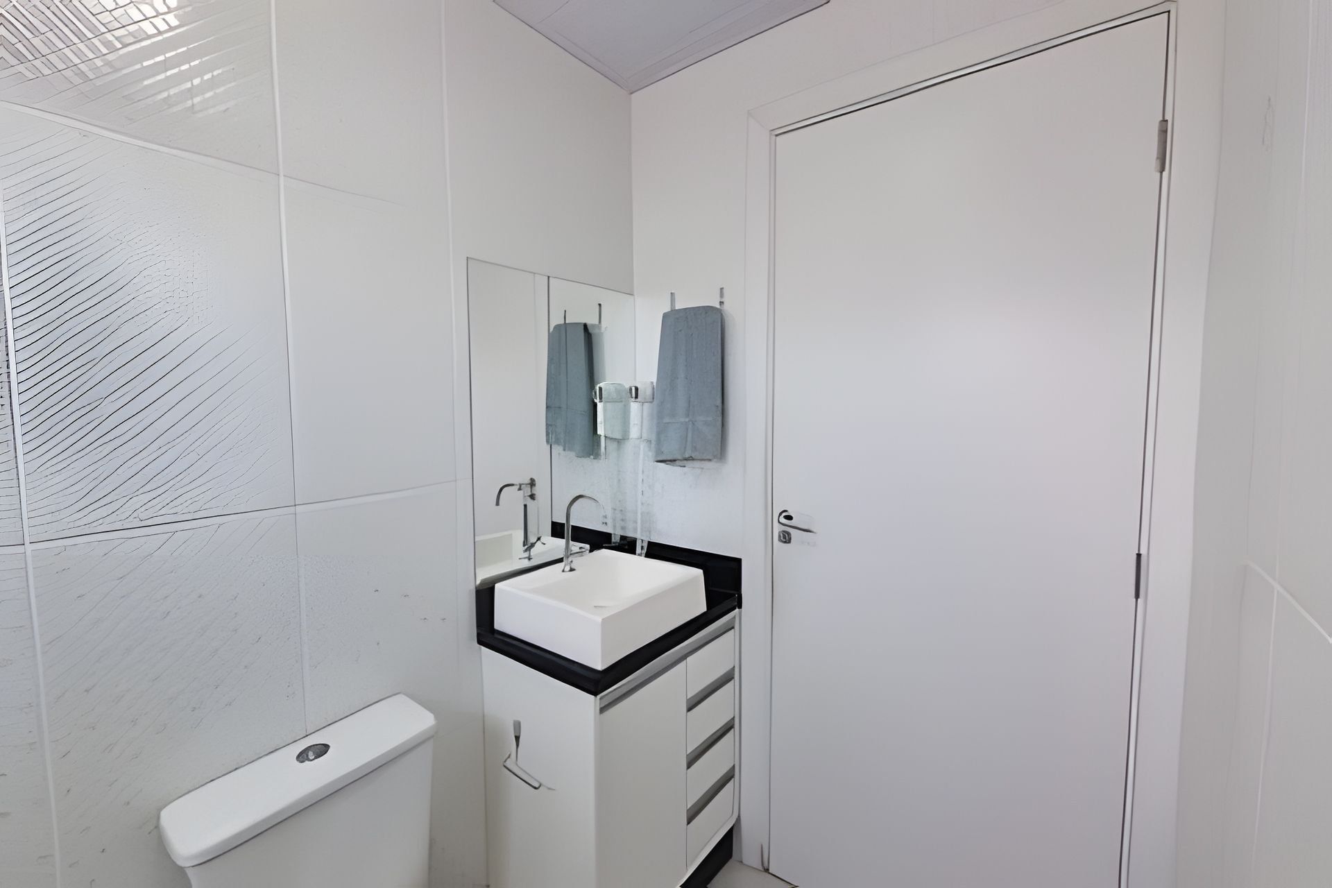 A small, clean bathroom with a white sink, mirror, and towel rack.