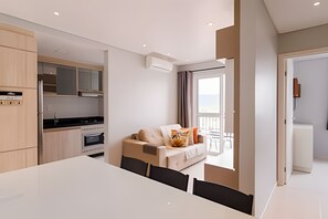 A modern apartment with a dining area, kitchenette, and a balcony with a view. - Curta Praia do Quilombo - Palladium  (Penha)