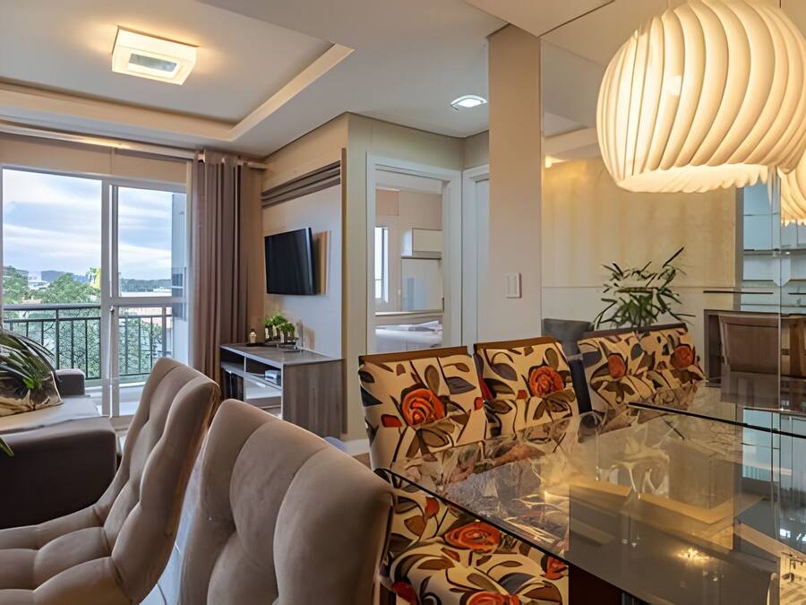 Una sala de estar moderna con un sofá, una mesa de comedor de vidrio y un televisor montado en la pared.