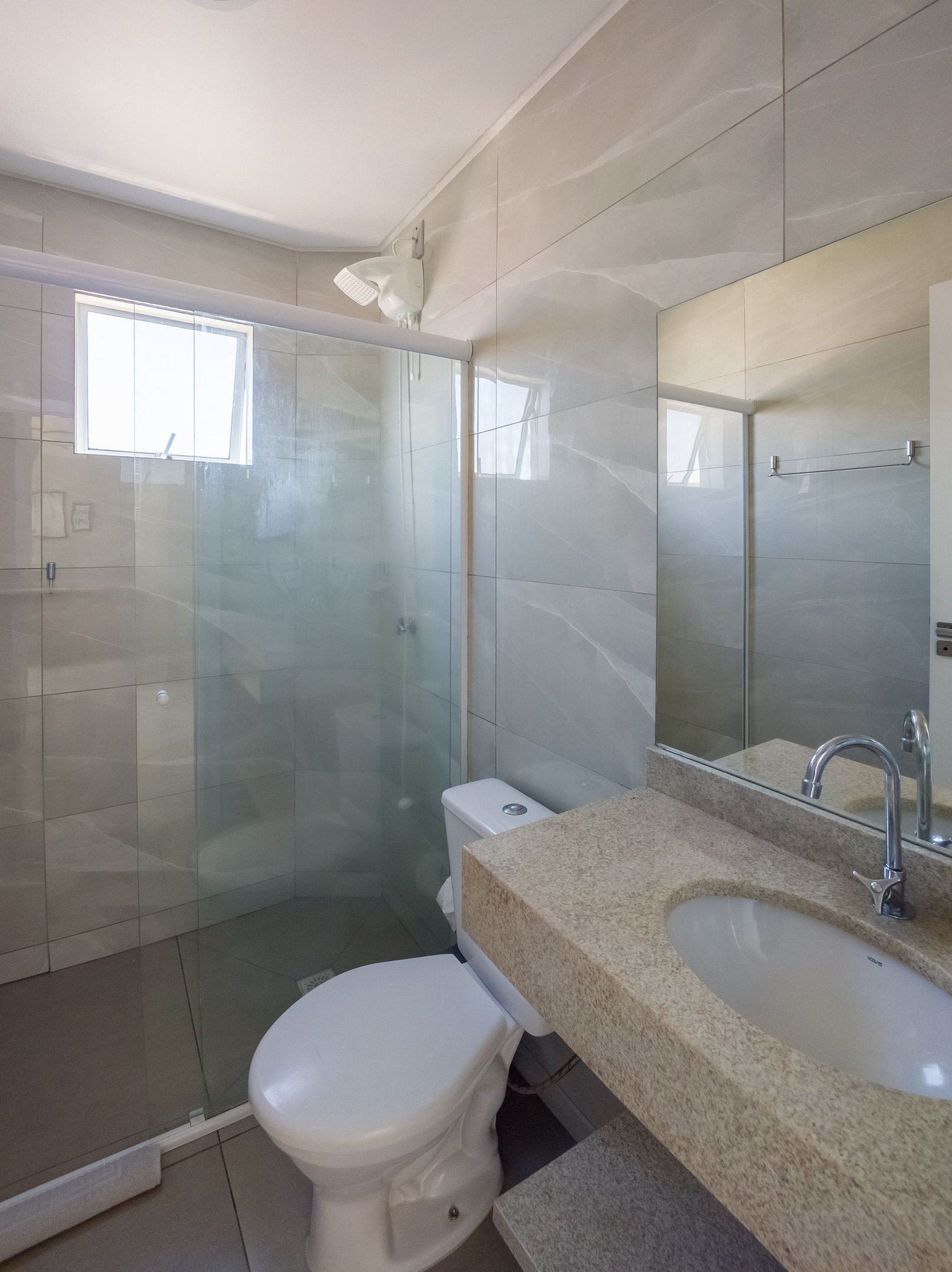 Een moderne badkamer met een douchecabine van glas, een toilet en een wastafel met spiegel.