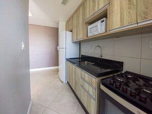 Una cocina con armarios de madera, un microondas, un lavamanos y una estufa.