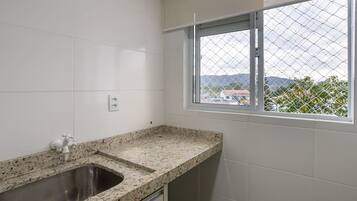 Una cocina con encimera de granito, pileta de acero inoxidable y ventana con vistas al exterior.