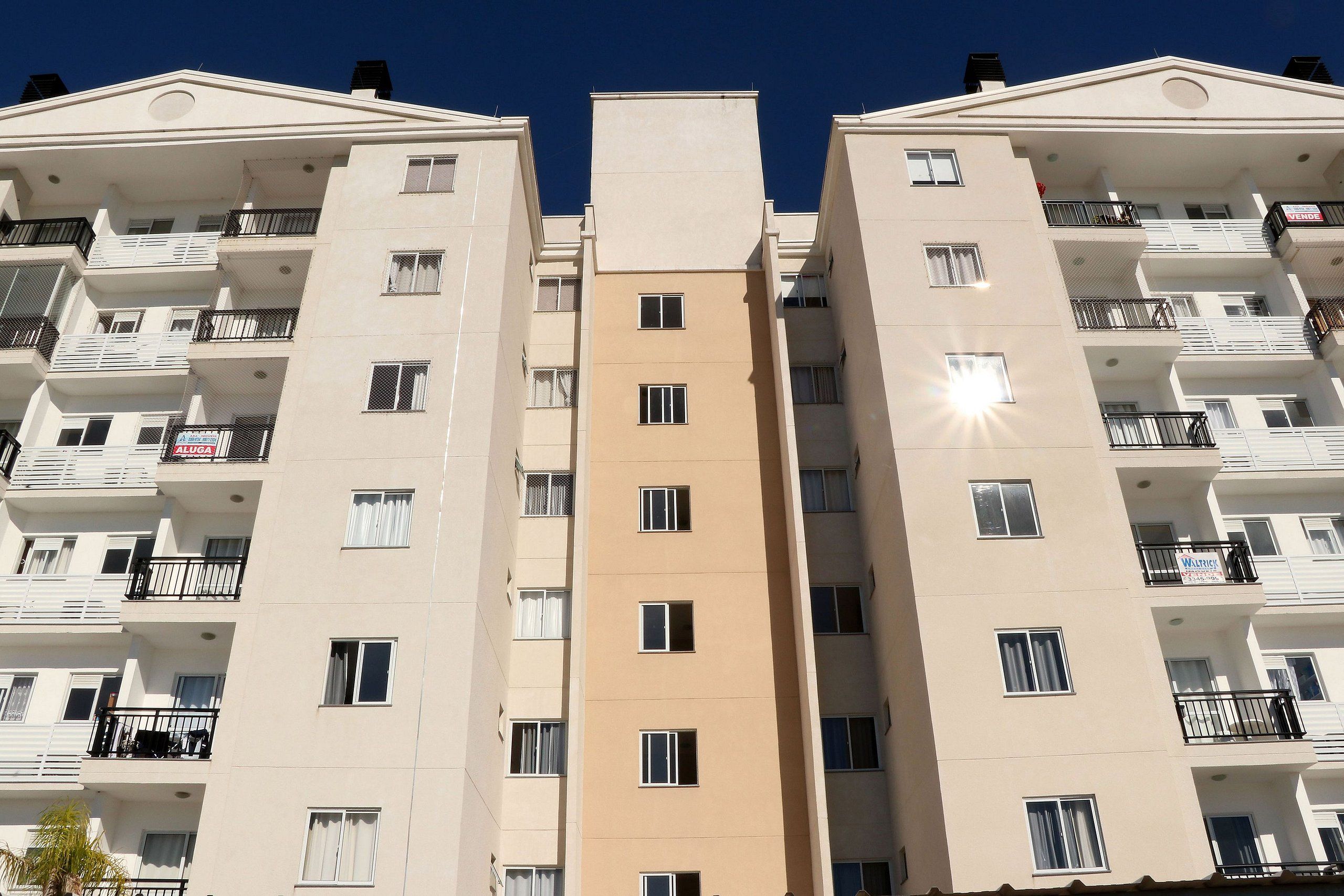 Un edificio residencial de varios pisos con balcones, una entrada principal y cielo despejado.