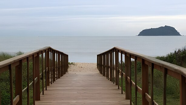 A wooden boardwalk leading to a beach with a view of the sea and a distant island. - Curta Praia do Quilombo - Palladium  (Penha)