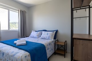 Une chambre à coucher avec un lit, un banc en bois et un bureau avec une chaise.