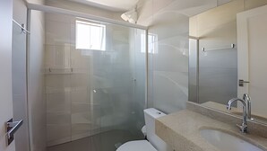 A modern bathroom with a glass shower enclosure, a white toilet, and a sink with a beige countertop. - Curta Praia do Quilombo - Palladium  (Penha)