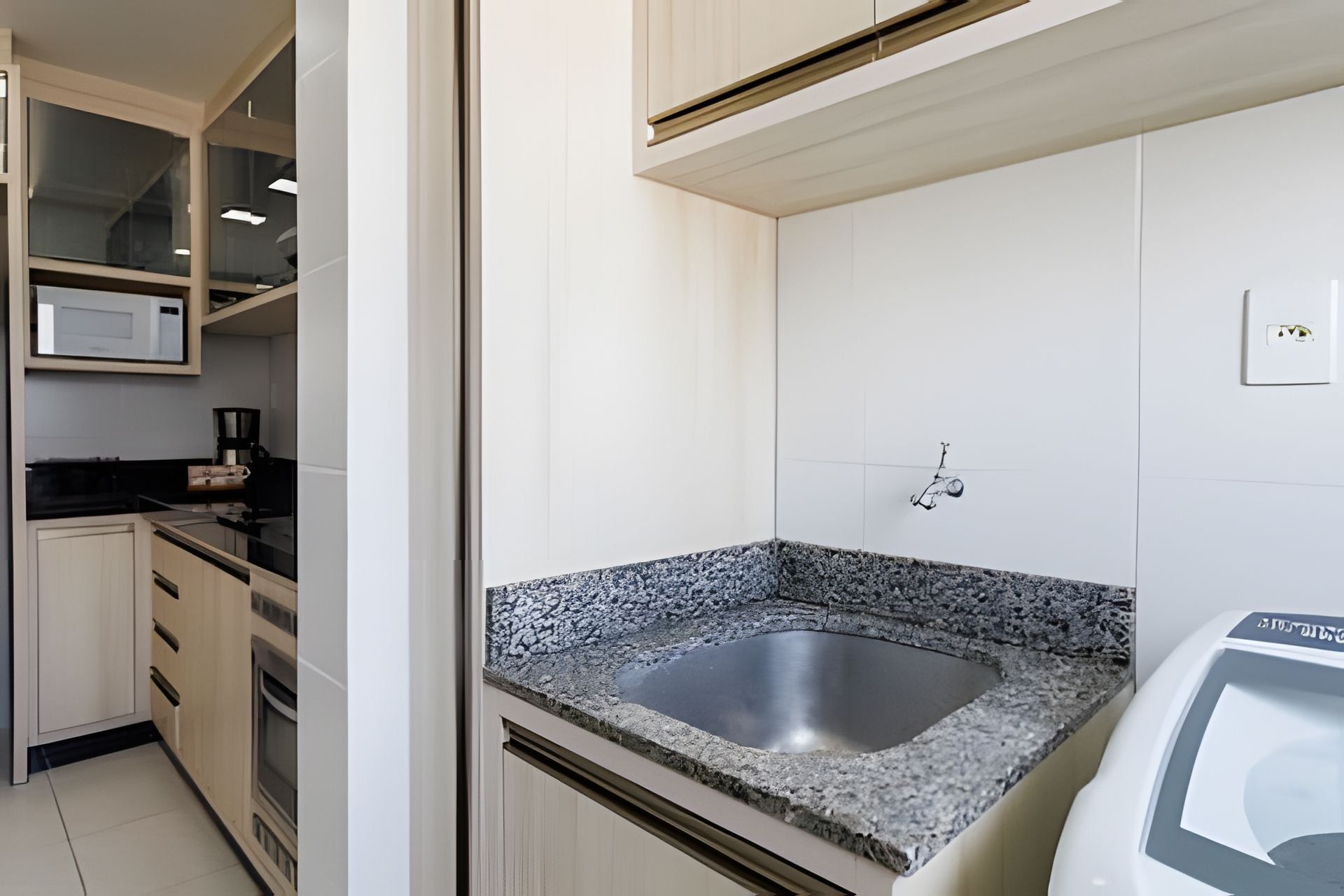 Een moderne keuken met granieten aanrechtbladen, een roestvrijstalen spoelbak en witte keukenkastjes.