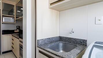 Una cocina moderna con encimeras de granito, un lavamanos de acero inoxidable y armarios blancos.