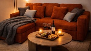 A cozy living room with a brown sofa, a round wooden coffee table, and a lit candle.