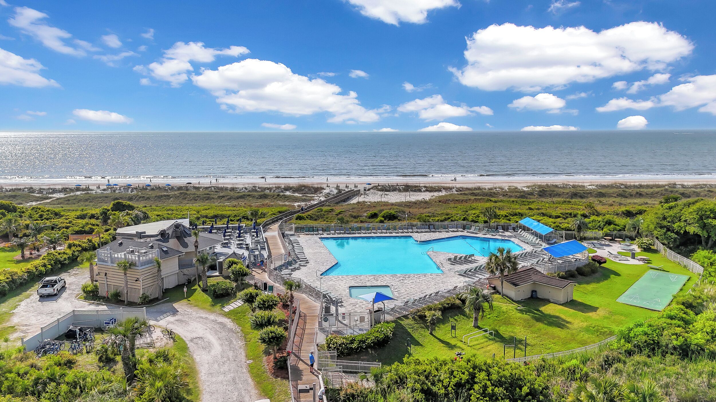 A resort with a swimming pool, beach access, and lush greenery.