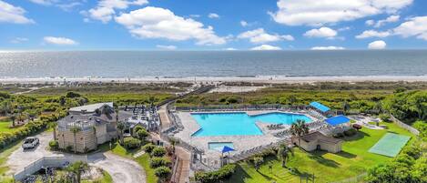 A resort with a swimming pool, beach access, and lush greenery.