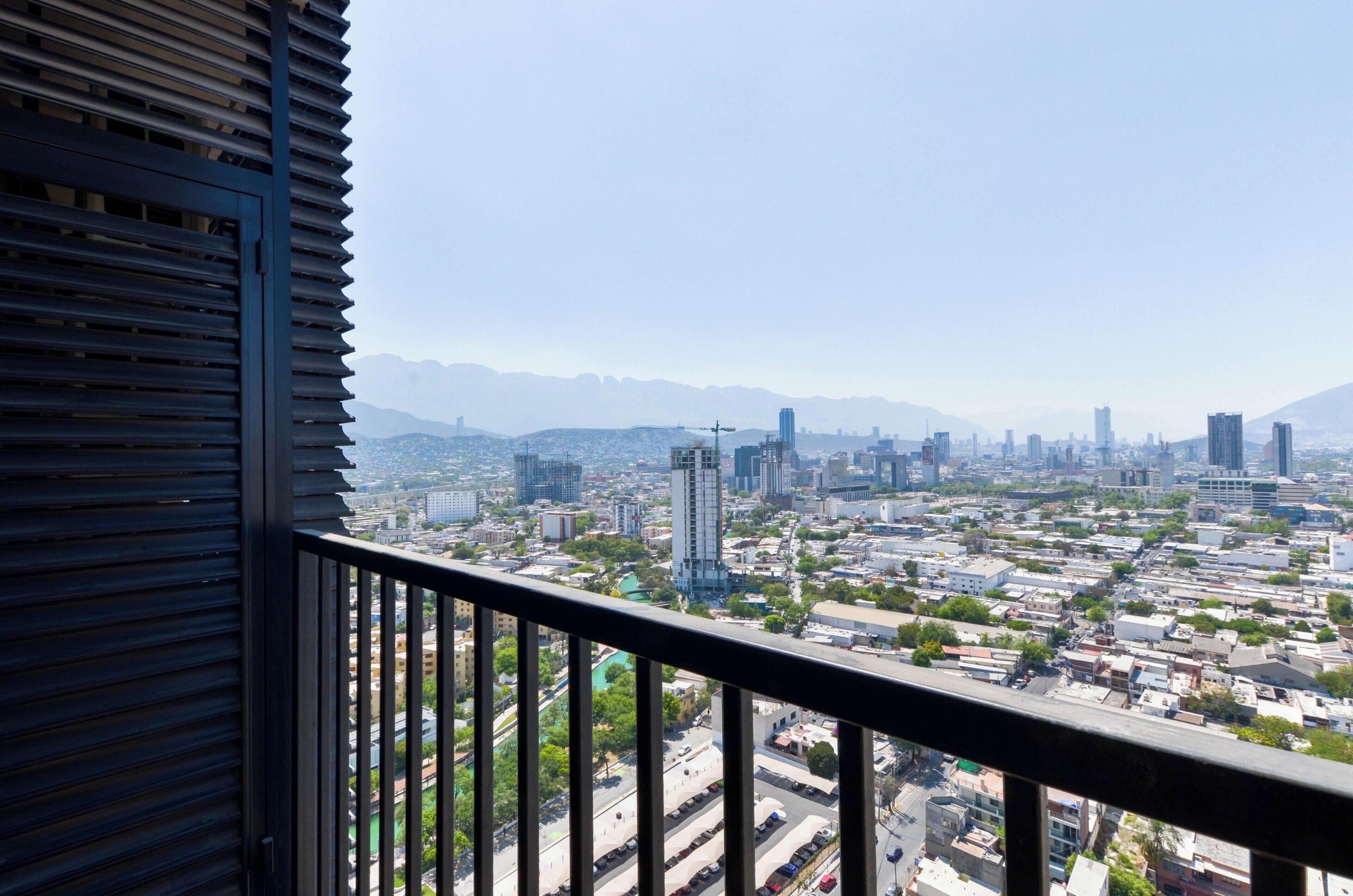 A cityscape viewed from a balcony with a metal railing.