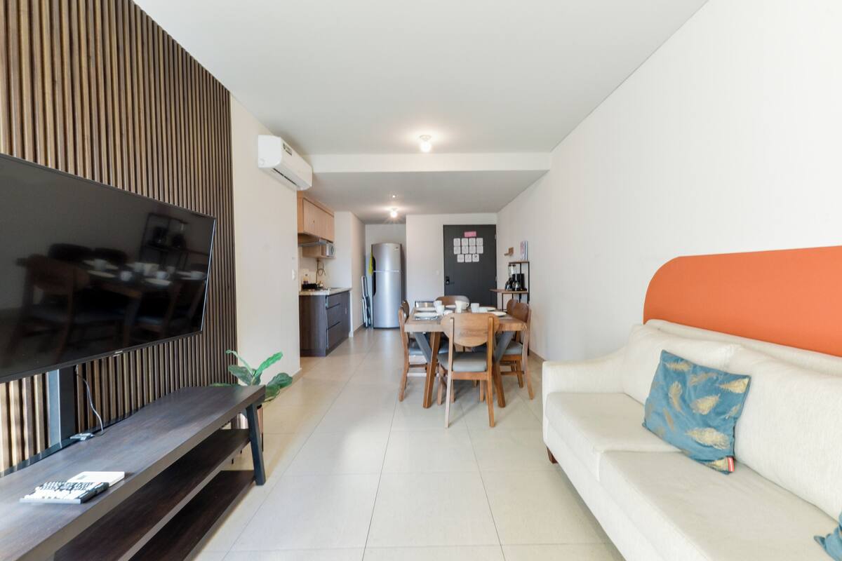 A modern living room with a TV, dining table, and sofa.