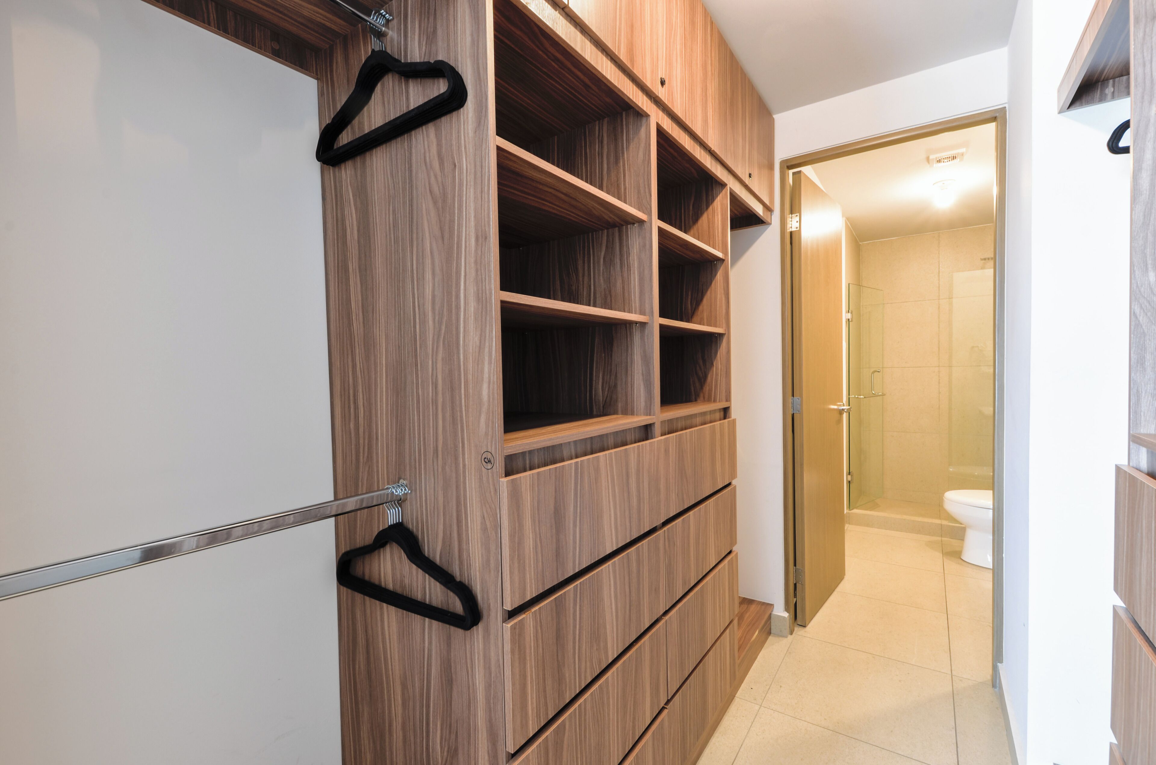 A walk-in closet with wooden shelves and a metal handle.