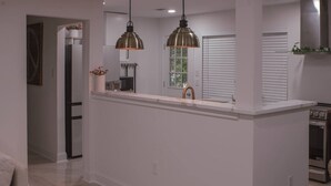 A modern kitchen with a central island, pendant lighting, and a view of the dining area.