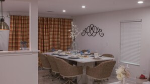 A dining area with a table set for four, surrounded by wicker chairs.