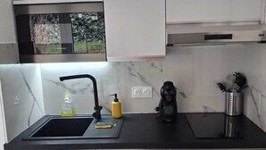 Een moderne keuken met een zwart aanrecht, roestvrijstalen apparatuur en witte kasten.