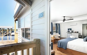 Una habitación con cama, escritorio, silla, ventilador de techo y vistas al exterior.