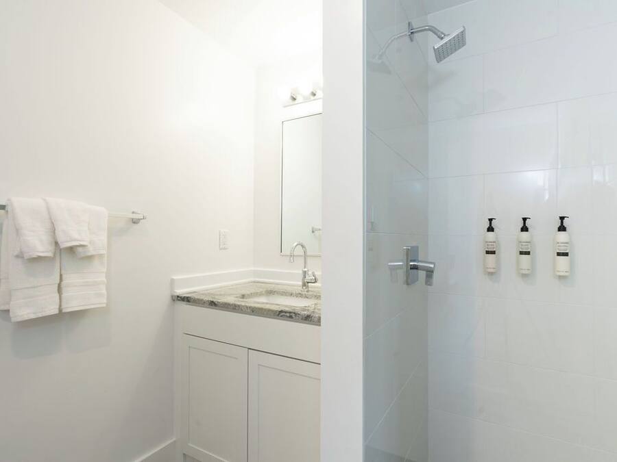 A bathroom with a sink, mirror, towel rack, and shower.