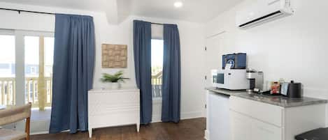 A modern kitchen with white cabinets, a countertop, and an air conditioning unit.