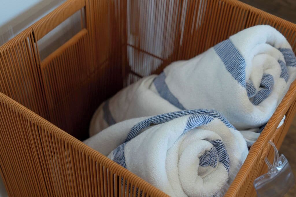 Una cesta de mimbre con toallas enrolladas con rayas azules.
