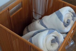 Una cesta de mimbre con toallas enrolladas con rayas azules.